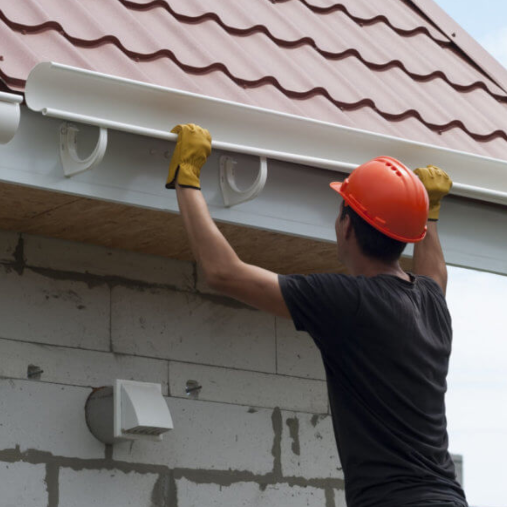 Worker cleaning the roof and gutters of a house.