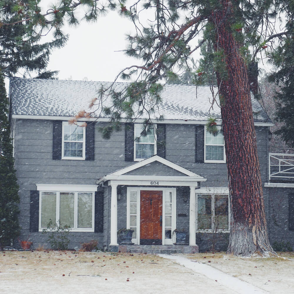 Front view of a house during winter after applying the correct ways to prevent roof problems during the winter.