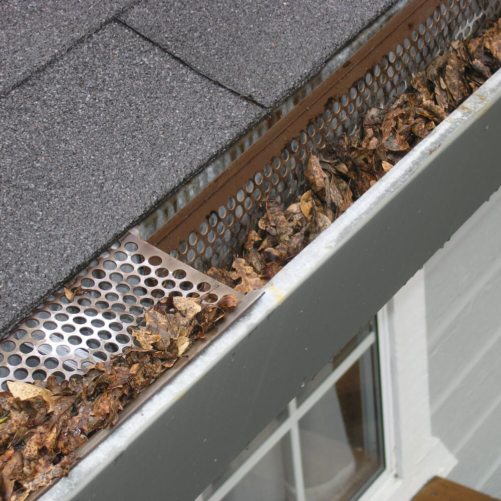 Close up photo of a roof needing roof maintenance because of clustered gutters.