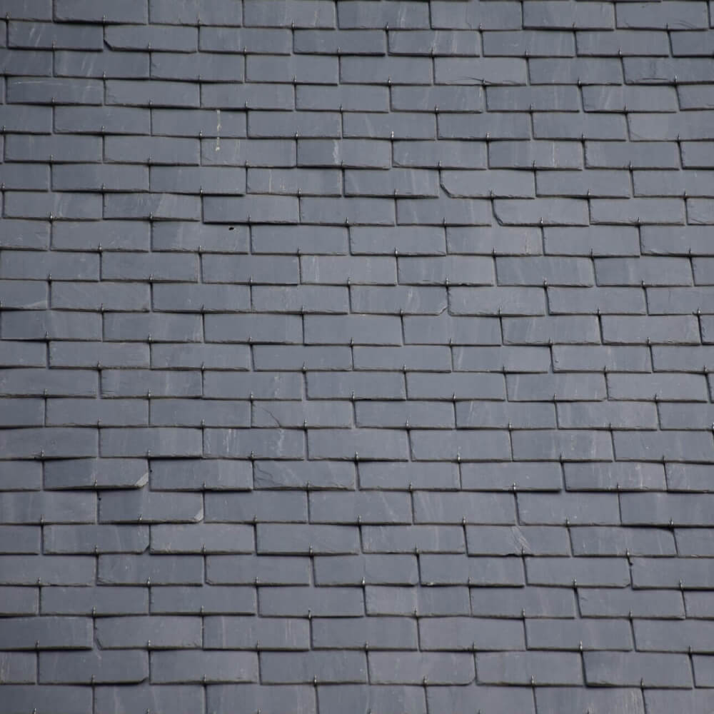 Close up of a roof's slate roof tiles in good condition after having their maintenance done by McCoy Roofing.