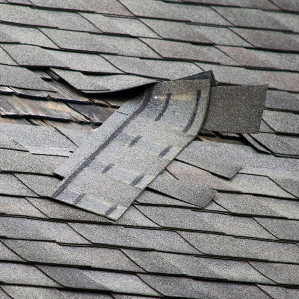 Close up of a roof's loose shingles after a storm.