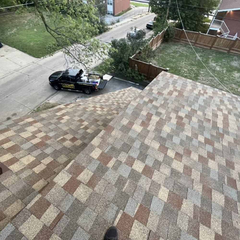 McCoy Roofing's worker on the roof working, company's truck below.